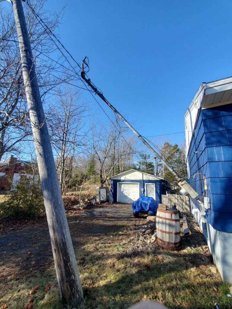 Damaged overhead service mast pulled away from a house, before emergency repair